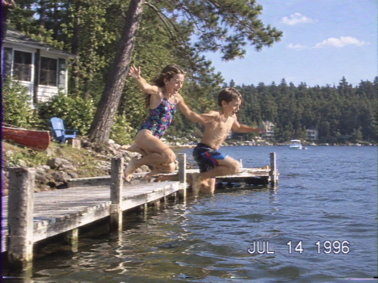 A home video frame of children jumping from a dock in 1996.